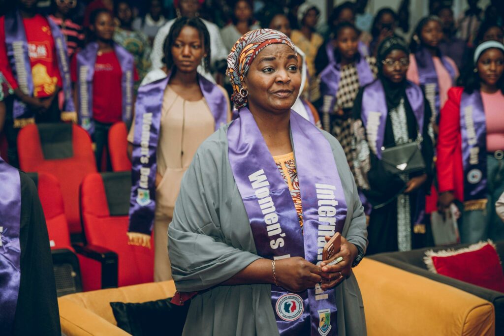 Women attending an International Women's Day celebration wearing purple sashes.
